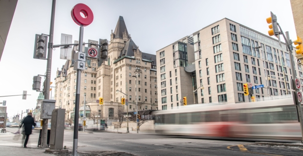 L’intersection de la rue Rideau et de la promenade Sussex avec un autobus en mouvement, un poteau de signalisation du train léger sur rail et le Château Laurier