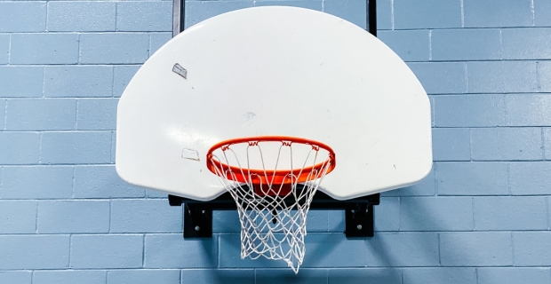 A basket ball hoop and backboard attached to a gym wall