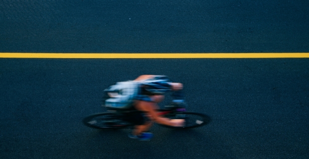 Vue aérienne d’un cycliste flou roulant à toute vitesse sur une nouvelle piste cyclable